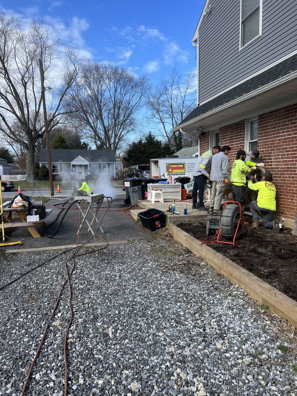 Pipeline Excavation crew working on underground sewer and utility service at a residential property